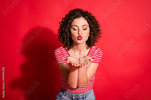 Photo of lovely wavy young woman dressed striped outfit sending you kiss closed eyes isolated red color background