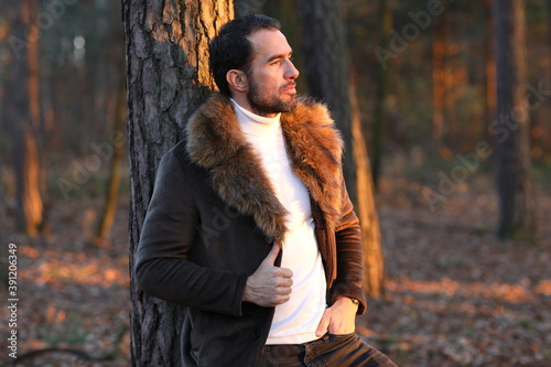 Przystojny mężczyzna w brązowym płaszczu z futerkiem. 