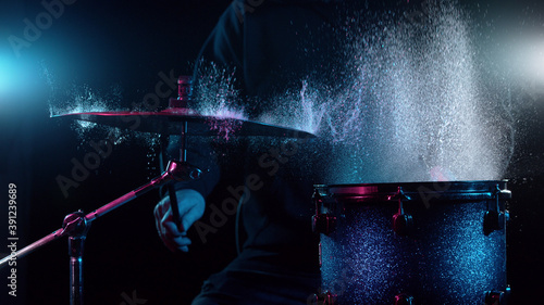 Freeze motion of drummer hitting drums with water splashes