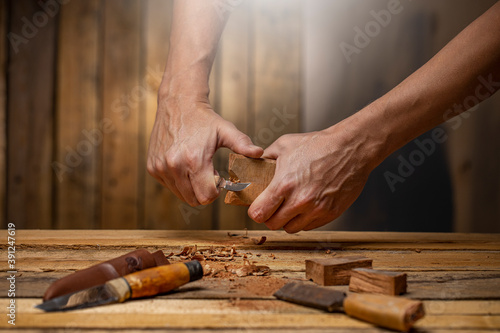Craftsman carving tools with a chisel carving knife a piece of dark wood on carpentry workbench 
