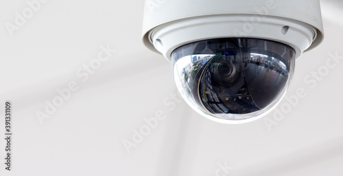 Closeup of white dome type cctv digital security camera installed on ceiling for observation.
