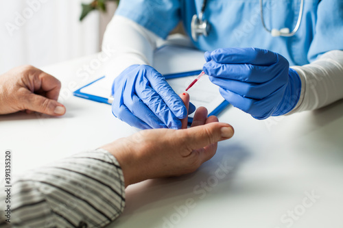 NHS UK doctor taking patient blood sample,serologic finger prick PRP blood antibodies test to determine whether person developed immunity to novel Coronavirus,global COVID-19 pandemic health crisis