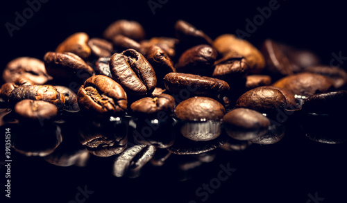 Coffee beans in brewed coffee. The concept of preparing aromatic strong coffee. Reflection of the grains in the liquid. Low key photography.