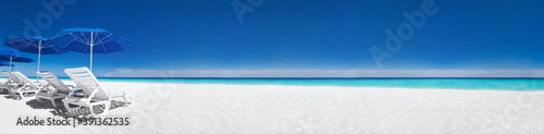 Caribbean beach with blue sun umbrellas and white beds. Tropical vacation