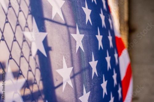 Illegal immigration concept Background of transparent American flag behind a chain link fence and concrete stairway