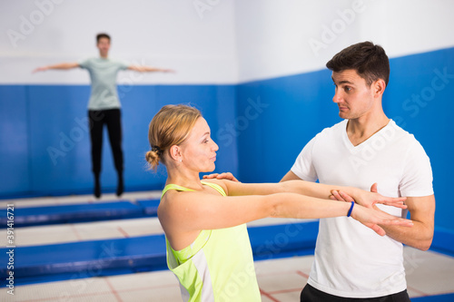 Experienced trampoline trainer teaching female gymnast of right technique in sports center..