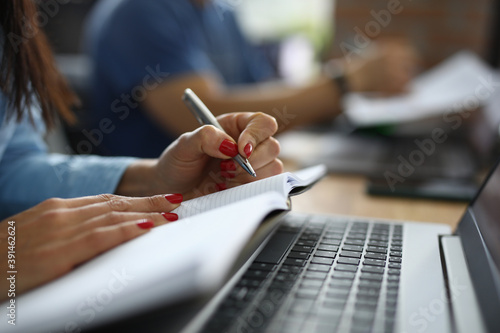 Female hands hold pen and diary next to laptop at work table. Training profession copywriter online concept