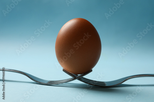 Forks with boiled eggs on blue background, close up