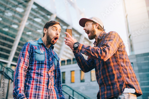 Men being happy winning a bet in online sport gambling application with football stadium on the background