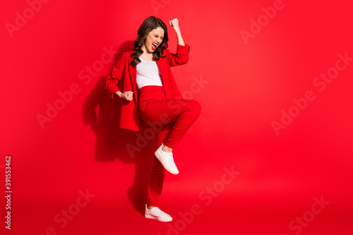 Full length profile photo of lovely girl raise fists open mouth eyes closed wear blazer pants footwear isolated red color background