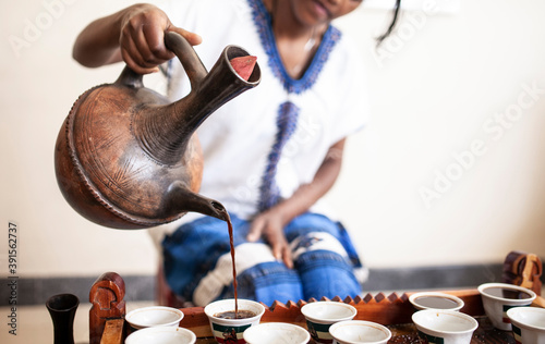 Closeup of womans hand as she serves coffee from a traditional pot in Ethiopia