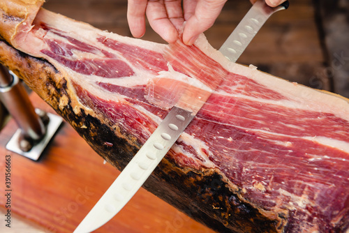 Manos cortando jamón ibérico con cuchillo