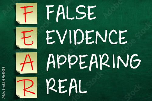 Motivating and inspiring FEAR acronym on sticky notes posted to chalkboard meaning False Evidence Appearing Real.