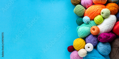 Knitting flat lay. Various colored balls of yarn on a blue background. Space for text