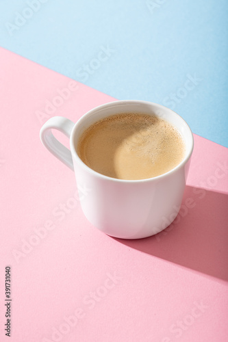 cup of coffee on a pastel pink and blue background, photography with contrast shadow