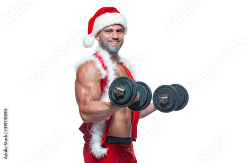 Sexy Santa Claus. Bodybuilder young handsome santa clause smile holds a dumbbells and shows off abs cubes at New Years eve and Christmas winter holiday white background.