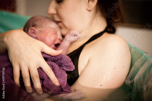 Mother Holding Newborn Baby in Birthing Pool After Home Birth