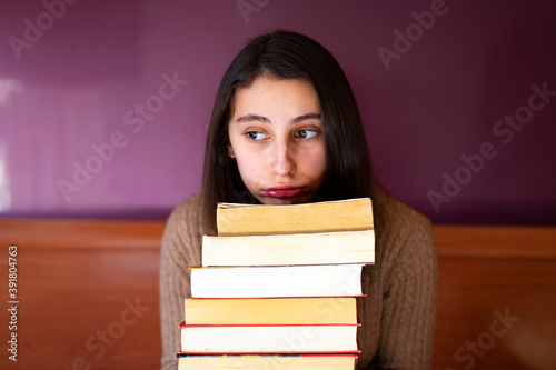 Stressed woman with a pile of books.