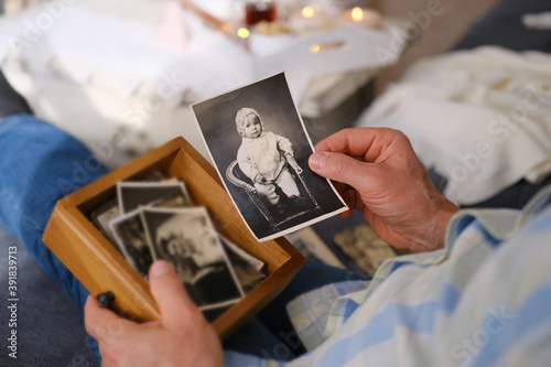 an elderly man looks through his old photographs of 1960-1965, the concept of nostalgia and memories of youth, childhood, remembering his life, relatives, family connection of generations