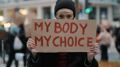 Woman holding a sign My Body, My Choice. Protest against tightening of the abortion law . Nationwide women's strike. Wearing protective face mask against COVID-19 Coronavirus. High quality photo