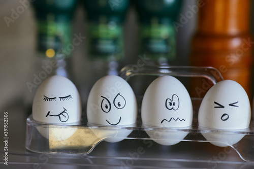 Funny smiling faces on chicken eggs. Four eggs in a box on a blurred background. Types of temperaments. Sanguine, choleric, phlegmatic and melancholic.