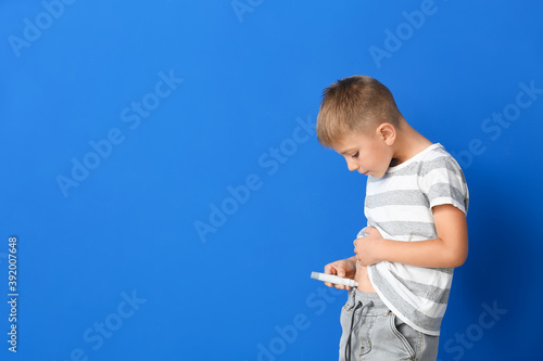 Little diabetic boy giving himself insulin injection on color background