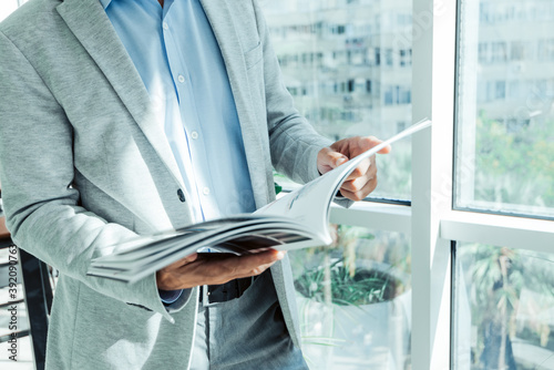 businessman in a business suit reads a magazine near the window with a plant