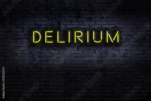 Neon sign. Word delirium against brick wall. Night view