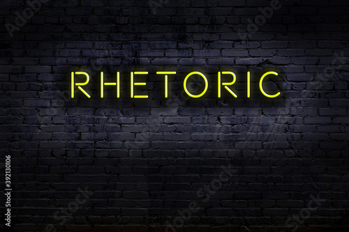 Night view of neon sign on brick wall with inscription rhetoric
