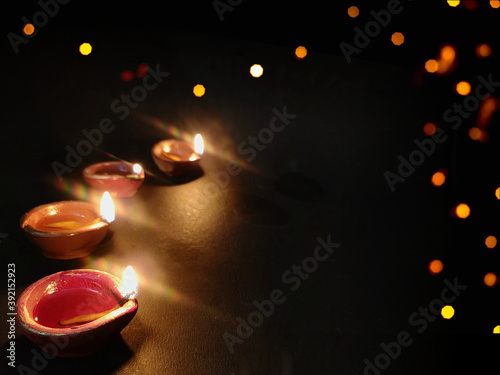Diya or deep burning arranged in row on black background with Space for text ,Happy diwali wallpaper
