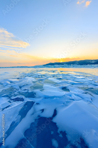 Transparent blue hummocks Baikal ice is shining through the crack sunset
