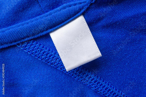 Blank white laundry care clothes label on blue fabric texture background