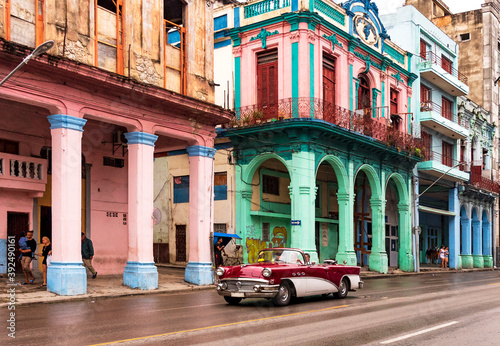 convertible classic car in front of colorful houses in havana cuba