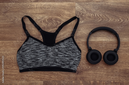Sports top bra and stereo headphones on wooden background. Sport and fitness. Getting ready for training. Top view. Flat lay
