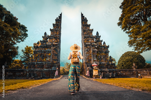 Woman with backpack walking at big entrance gate in Bali, Indonesia.