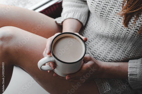 Cup of coffee in hands close-up. Woman in knitted sweater holding a cup of coffee