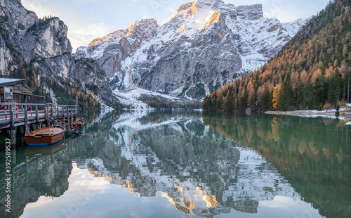 The beautiful, scenic view of Braies Lake, in the Dolomite mountains, in the Trentino Alto Adige region. Mountains reflecting in the still water, wooden house and a docked boat. Postcard magic