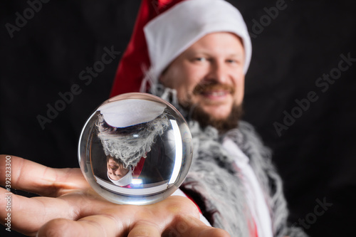Cheerful Santa dressed in fur skin with crystal spehre