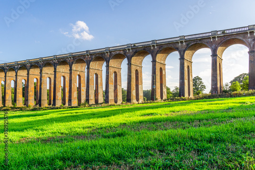 A view of the Ouse Valley Viaduct (Balcombe Viaduct) in the summer with bright sun shining through the arches onto the grass