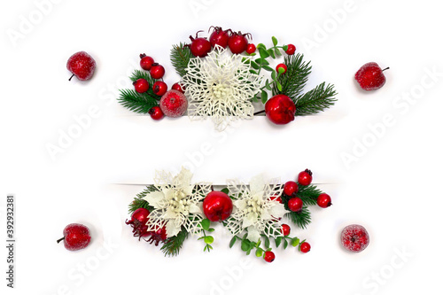 Christmas decoration. White openwork flowers poinsettia, branch christmas tree, red berries, apples and white paper card note with space for text on white background. Top view, flat lay