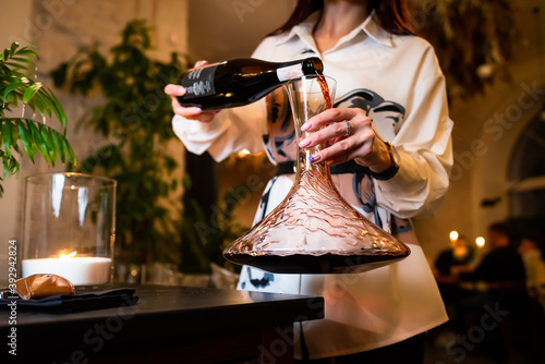 woman sommelier decanting red wine . woman sommelier pouring red wine into the decanter. 
