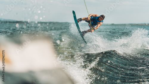 young man doing wakeboarding in a lake whit mountains also doing jumps