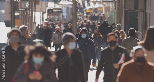 Anonymous crowd of people walking street wearing masks during covid 19 coronavirus pandemic