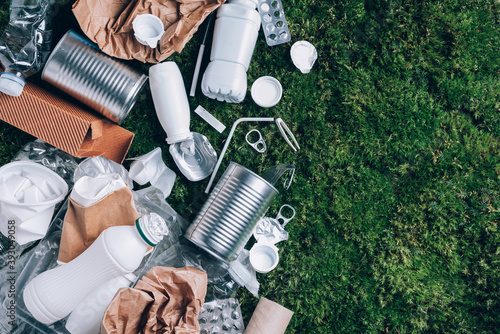 Reuse garbage, recycle, plastic free. Food plastic packaging, trash on green moss background after picnic in forest. Top view. Copy space. Recycling plastic. Environmental pollution, ecology concept.