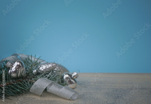 The christmas spruce sprig with silver decorations on wooden background with blue background
