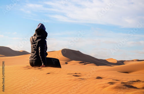 A woman is sitting on the golden sand dune of the Namib desert