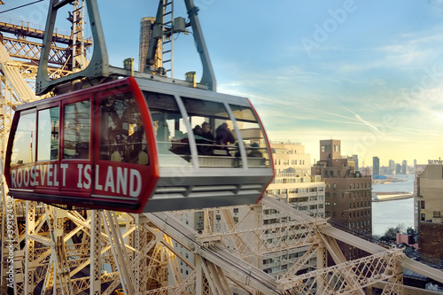 New York, USA - December 24, 2019: Cabin of the famous Roosevelt Island cable car in front of the Ed Coch Queensboro Bridge from Manhattan to Queens in New York.