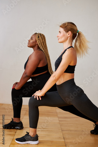 sporty differents women do fitness exercises together isolated in studio, slim and cubby mixed race women in sportswear