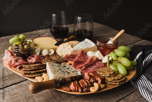 Close up of charcuterie board and glasses of wine on wooden table.