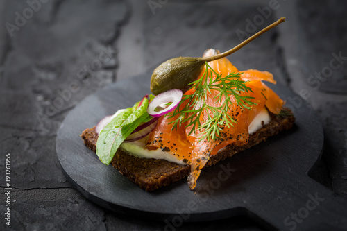 Salmon open sandwich on Pumpernickel bread with vegetables, herbs and soft cheese